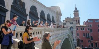 Masked and standing apart, the world tiptoes out of lockdown